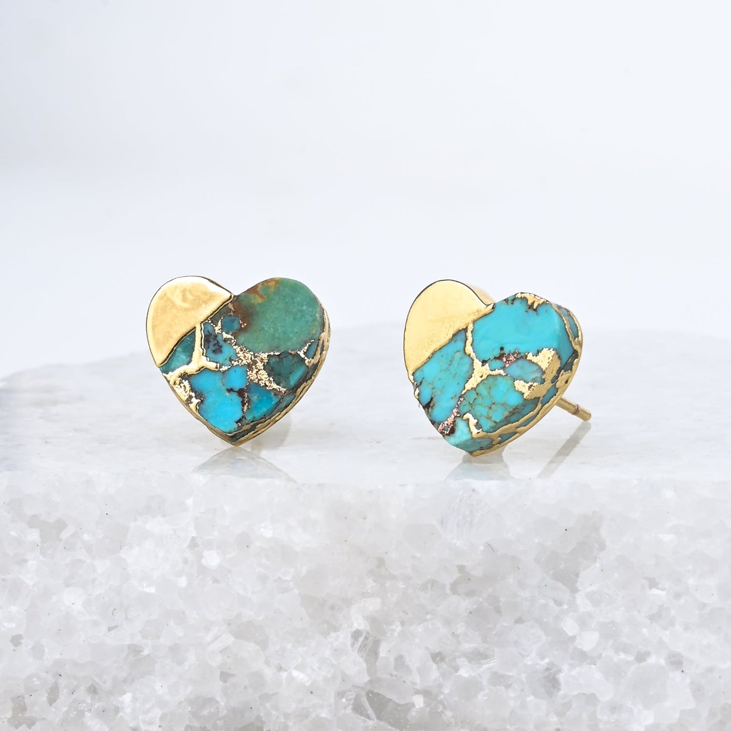 Heart-shaped earrings with turquoise and gold finish on a white background
